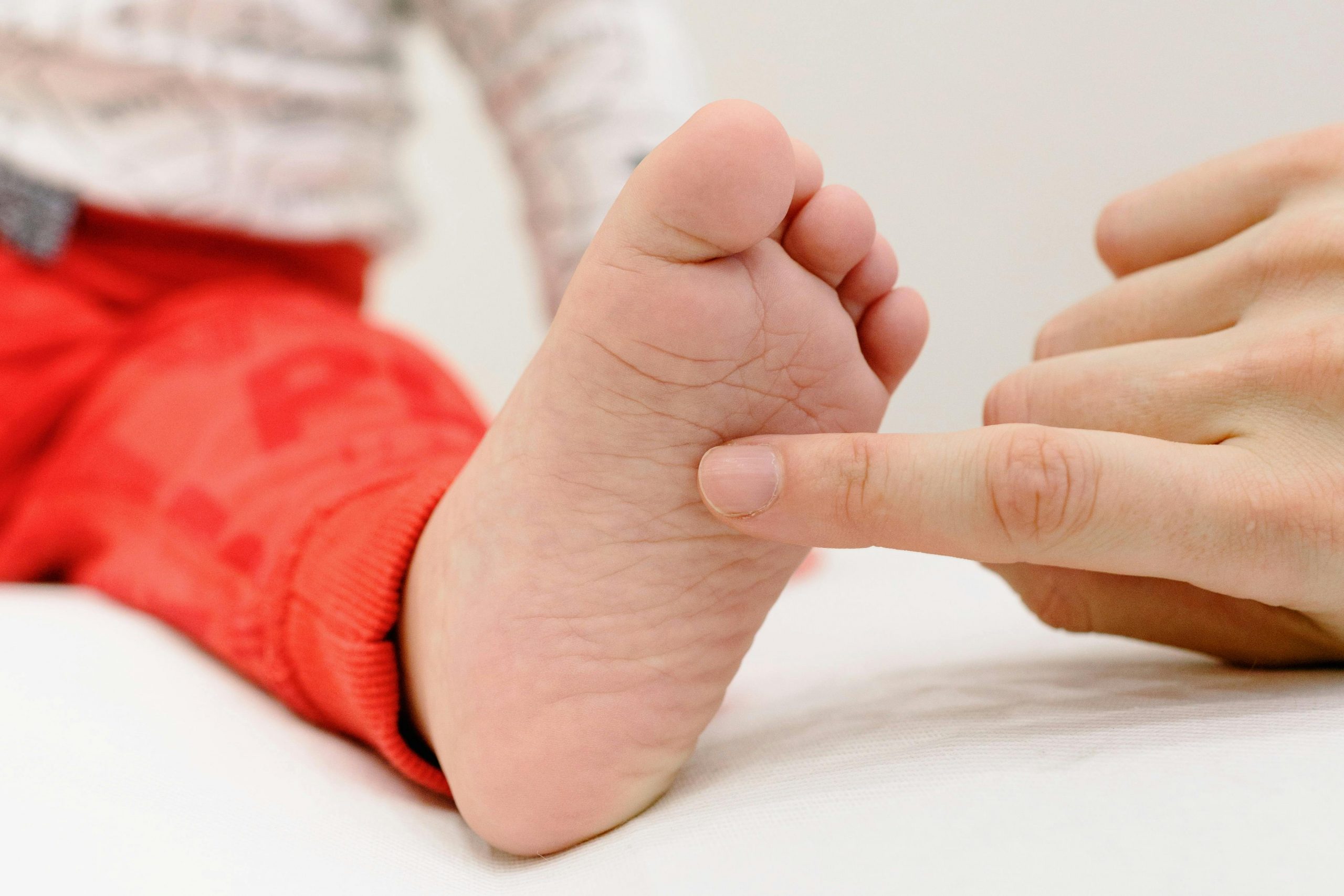 Séance de réflexologie plantaire enfant à Fontainebleau — praticienne montrant un point réflexe au parent